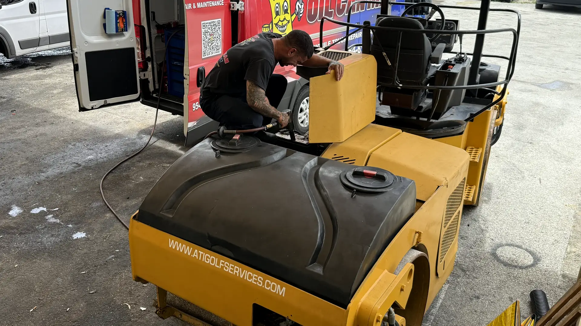 An Oil Can Man technician servicing a road roller on site in South Florida